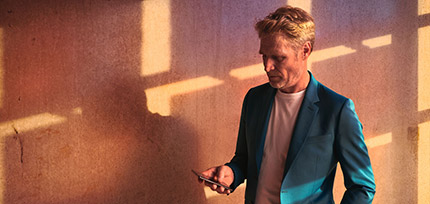 Ein Mann von vorne im Anzug schaut auf sein Handy