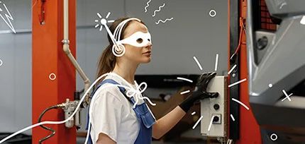 Eine Werkstattmitarbeiterin der VGRD mit Superheldenmaske beim Bedienen einer Hebeb&uuml;hne