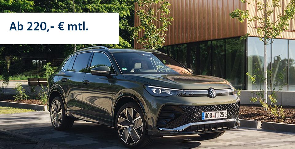 Ein Tiguan R-Line in der Dreiviertelansicht von vorne parkend am Stra&szlig;enrand mit einem Geb&auml;ude im Hintergrund