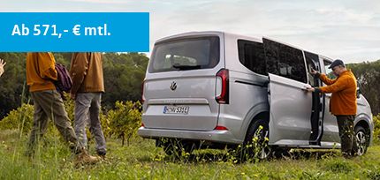 Silberne e-Caravelle Life stehend auf einer Wiese mit B&auml;umen im Hintergrund