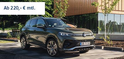Ein Tiguan R-Line in der Dreiviertelansicht von vorne parkend am Stra&szlig;enrand mit einem Geb&auml;ude im Hintergrund